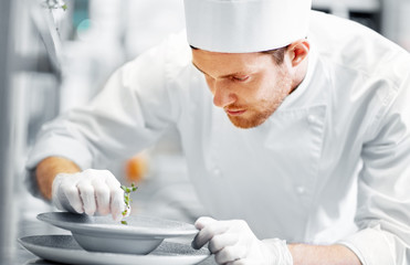 food cooking, profession and people concept - happy male chef cook serving plate of soup at...