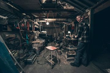 Young man standing inside dark messy barn.