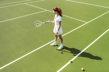 side view of young attractive woman in white tennis uniform playing tennis on court
