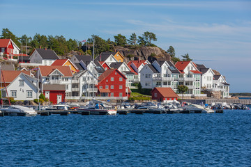 The traditional coastal wooden houses covered in sunlight in the Lyngor archipelago, Southern Norway