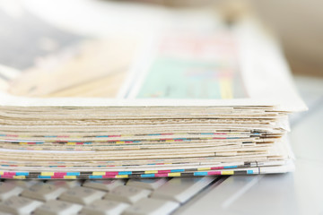 Newspapers and laptop. Pile of daily papers with news on the computer. Pages with headlines,...