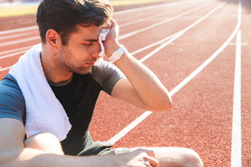 Exhausted sportsman finished running at the stadium