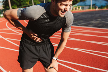 Tired sportsman finished running at the stadium