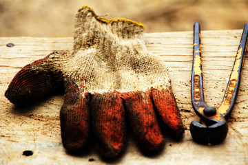 Closeup old gloves and combination cutting pliers put on the wood plank.