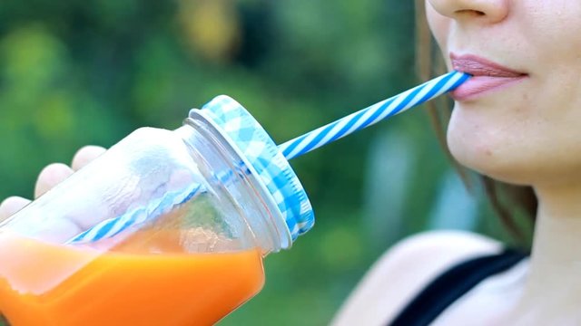 Woman drinks smoothies or orange fresh outdoors.