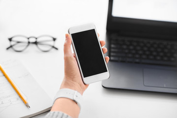 app design, technology and business concept - hand of businesswoman holding smartphone with black blank screen at office