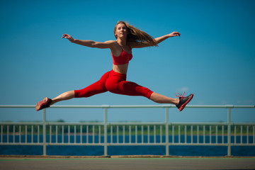 Young caucasian girl performs twine jumping on sky backround.