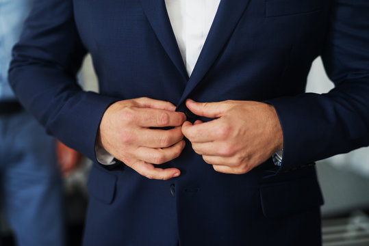 Mans hands teeing a button on beautiful waistcoat.
