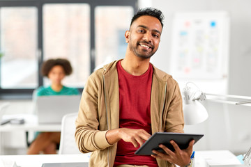 business, technology and people concept - happy smiling indian man with tablet pc computer at office