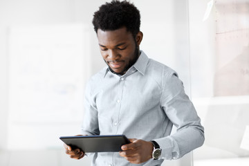 business, people and technology concept - african american businessman with tablet pc computer at...