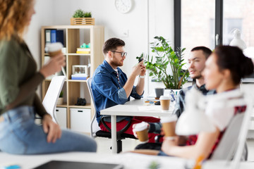 business, technology and people concept - creative man with smartphone at office coffee break