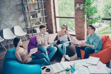 Teambuilding concept! Group of youth guy and cheerful girls sit in chairs bags near the table with...