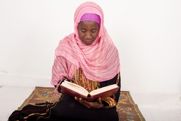 Muslim woman sitting praying reads the Koran