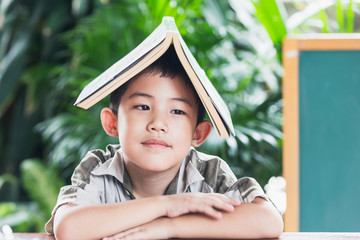 Asian little boy holding book on head,education concept