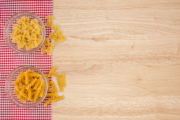 Pasta in a glass bowl on the old wooden table.