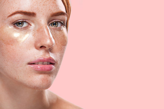 Beautiful model woman with ginger hair and frackles and gold patches for skin care