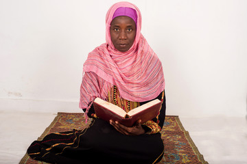 Muslim woman sitting praying reads the Koran