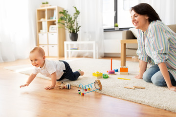 family, child and motherhood concept - happy mother with little baby boy and developmental toys at home