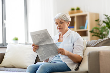 age and people concept - senior woman reading newspaper at home