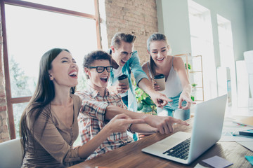 Four cheerful people, friends,  enjoying funny video tutorial, guys and girls pointing with fingers...