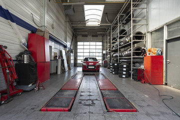 Red car during overhaul in a modern garage with a lift