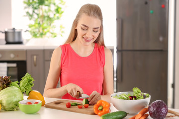 Obraz na płótnie Canvas Young woman preparing salad in kitchen. Diet food concept