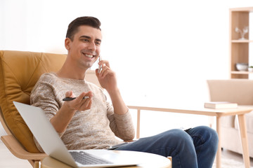 Young freelancer talking on phone at home
