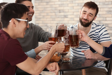 Group of friends clinking glasses with beer in bar