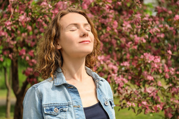 Portrait of beautiful woman near blooming tree in park