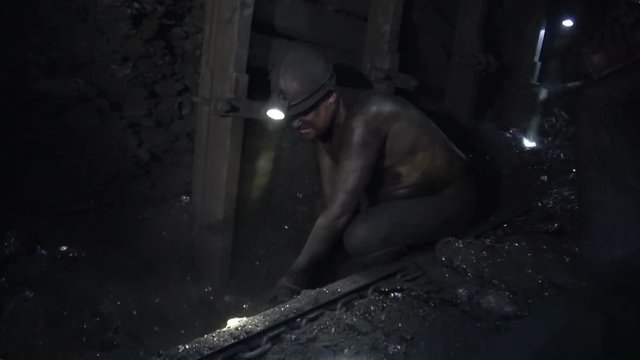Heavy work of miners in a coal mine. Hard labour. Solid fuel