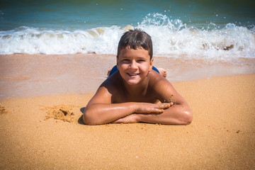 Fototapeta na wymiar Smiling boy lying on the beach, outdoors