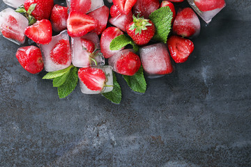 Ice cubes with strawberries and mint on dark background