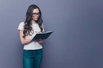 Attractive smart, clever, lovely stylish nice cute curly-haired brunette girl in casual white t-shirt, jeans and glasses, holding note-book, writing plans, copy-space, isolated on grey background