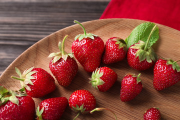 Ripe strawberries on wooden plate, closeup