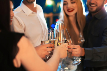 Young people clinking glasses with champagne at birthday party in club