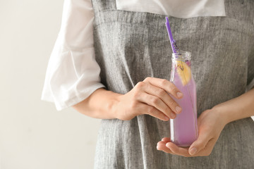 Obraz na płótnie Canvas Woman holding bottle with fresh lavender lemonade on light background, closeup