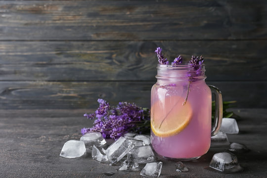 Mason jar with lavender lemonade and ice cubes on grey table