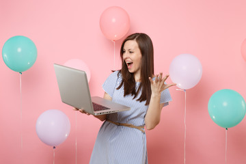 Portrait of overjoyed happy young woman in blue dress holding using laptop pc computer spreading...