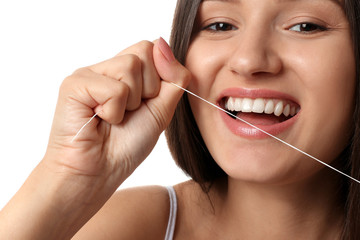 Young woman flossing her teeth on white background