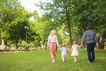 Naklejka na ściany i meble Happy family walking in green park