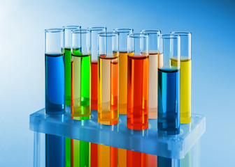 Test tubes with colorful liquids in holder on light background