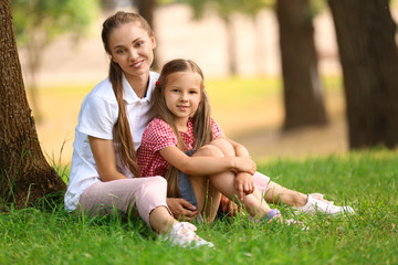 Happy mother and daughter resting in green park