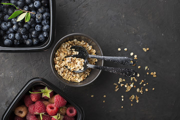 Black plastic containers take-away for a healthy snack food with raspberries, blueberries. Ingredients of healthy breakfast: granola, oat flakes, berries, nuts, apples, bananas. Top View.