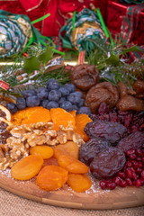 Platter of Festive Christmas Fruits.  Wooden Platter loaded with a selection of fresh and dried Christmas Fruits.  Decorated with Holly, Cinnamon and Christmas parcels.