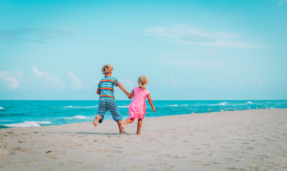 Naklejka premium little boy and girl running on beach