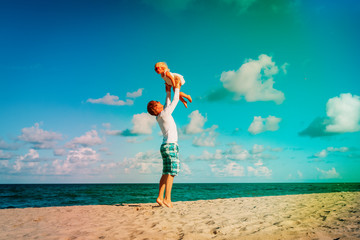 father and little daughter play at sky on beach