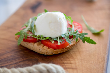Italian style toast with light bread, arugula, tomato and mozzarella cheese 