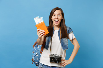 Young amazed woman student with retro vintage photo camera on neck holding passport, boarding pass tickets showing thumb up isolated on blue background. Education in college abroad. Air travel flight.