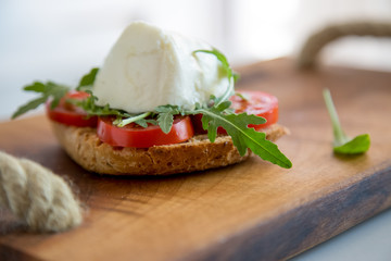 Italian style toast with light bread, arugula, tomato and mozzarella cheese 