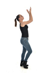  full length portrait of brunette girl wearing black single and jeans. standing pose in side profile. isolated on white studio background.